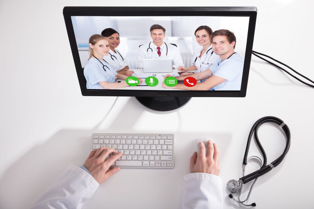 Doctor Video Conferencing With Medical Team On Computer